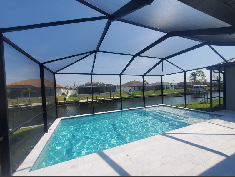 A screened in swimming pool with a view of the water