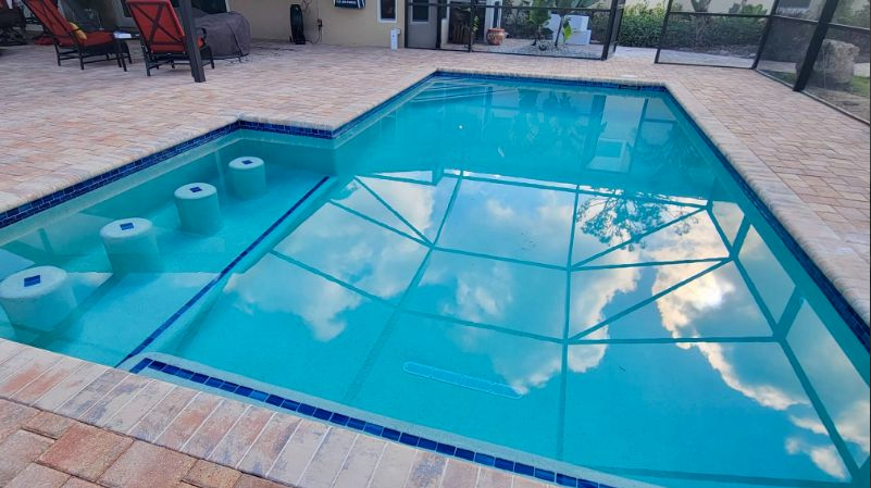 A screened in swimming pool with a view of the water