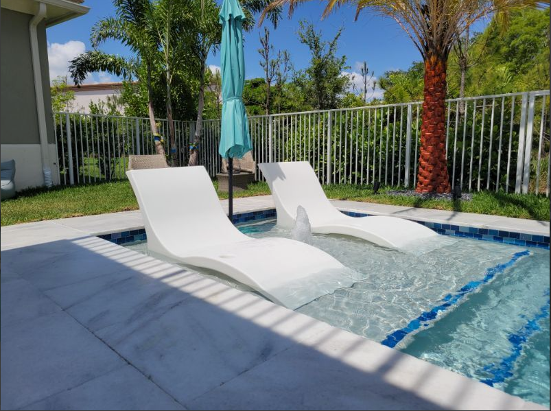 A swimming pool with two lounge chairs and an umbrella