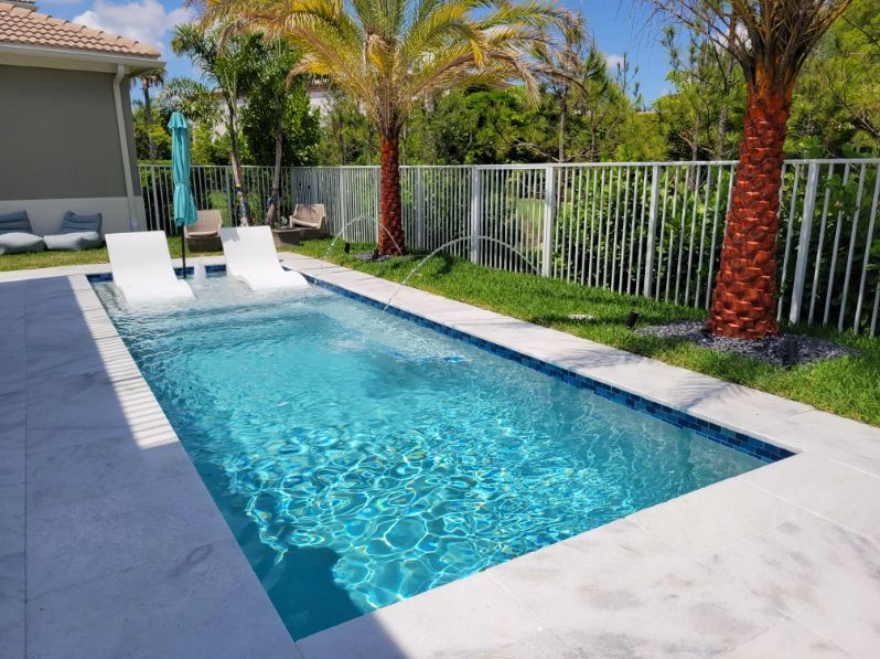 A large swimming pool surrounded by palm trees and a fence.
