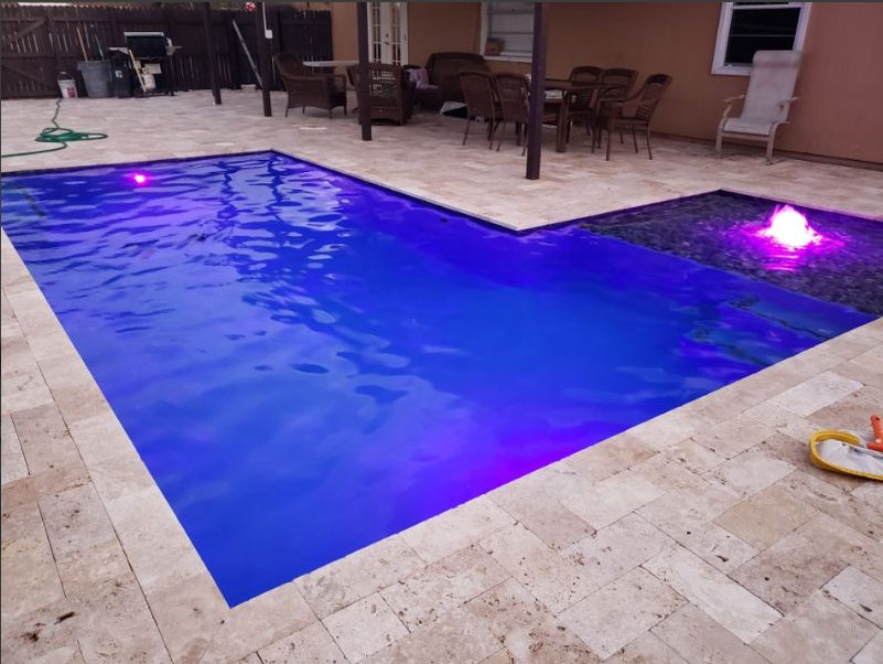 A large swimming pool with purple lights on it