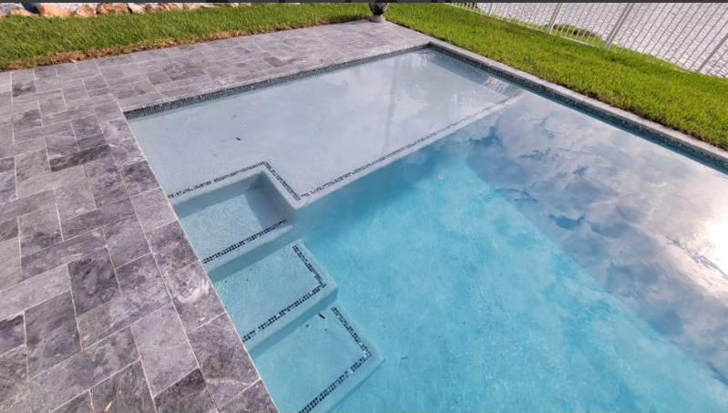 A large swimming pool with stairs leading to it in a backyard.