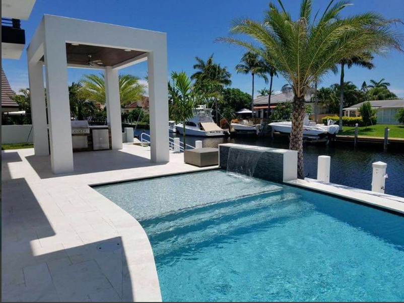 A large swimming pool surrounded by palm trees and boats