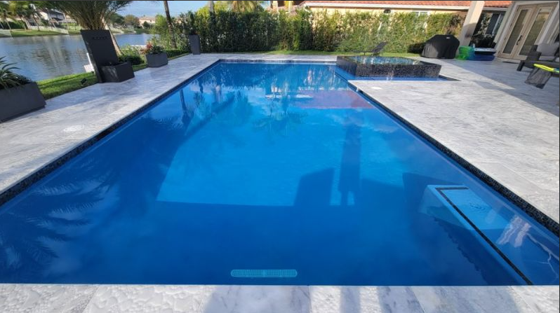 There is a large swimming pool in the backyard of a house.