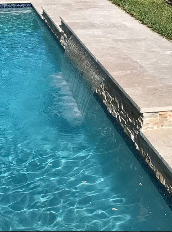A swimming pool with a waterfall in the middle of it