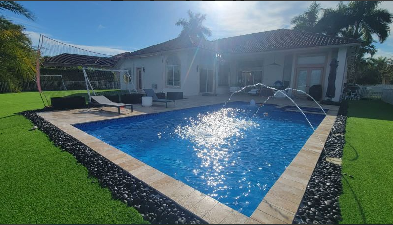 A large swimming pool with a fountain in front of a house