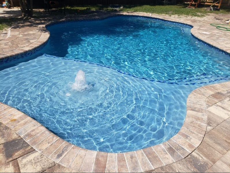 A large swimming pool with a fountain in the middle of it.