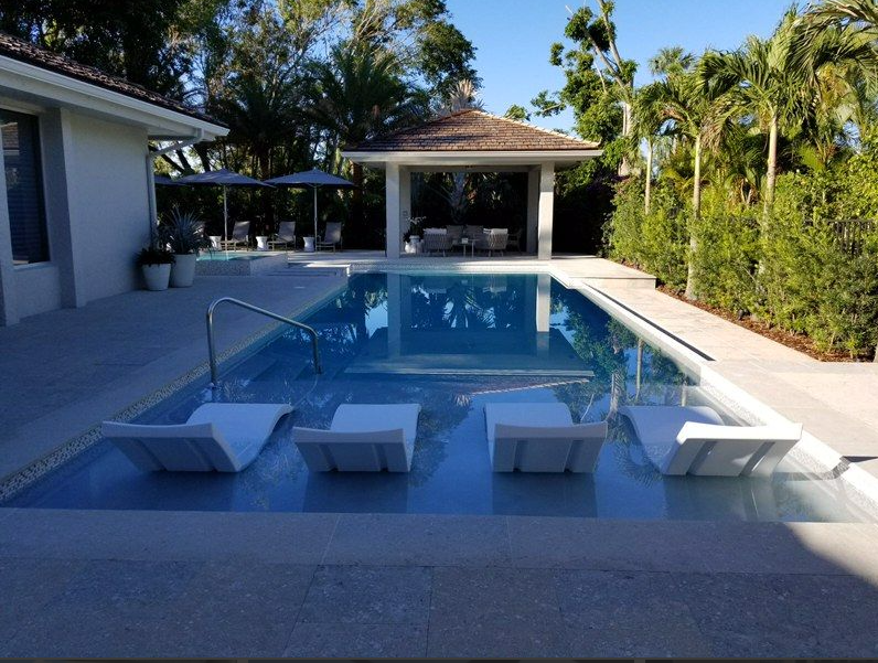 A large swimming pool with chairs and umbrellas in front of a house