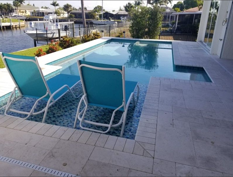 A swimming pool with two blue chairs in front of it