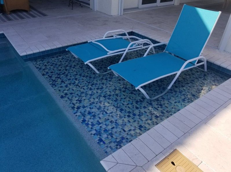 Two blue lounge chairs are sitting in a swimming pool