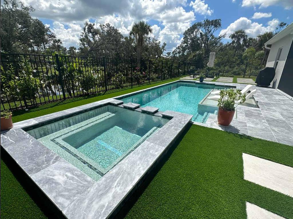 A large swimming pool with a hot tub in the middle of it.