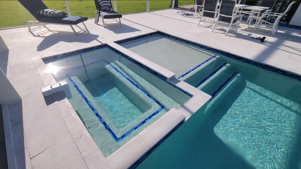 A large swimming pool with a hot tub in the middle of it.