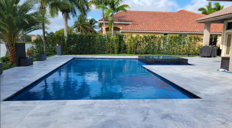 There is a large swimming pool in the backyard of a house.