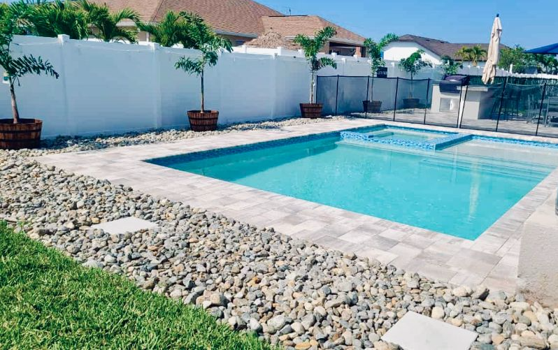 A large swimming pool in the backyard of a house next to a lake.