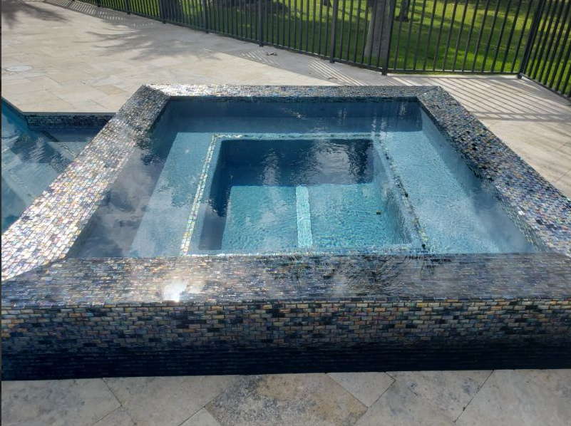 A swimming pool with a hot tub in the middle of it