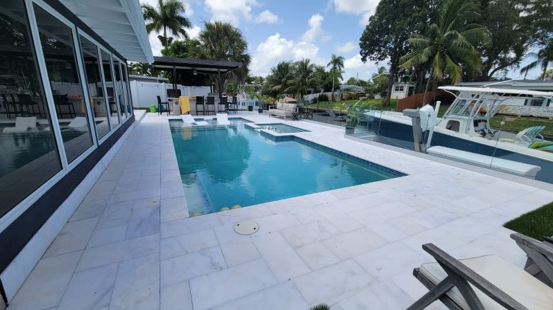 There is a large swimming pool in the backyard of a house.