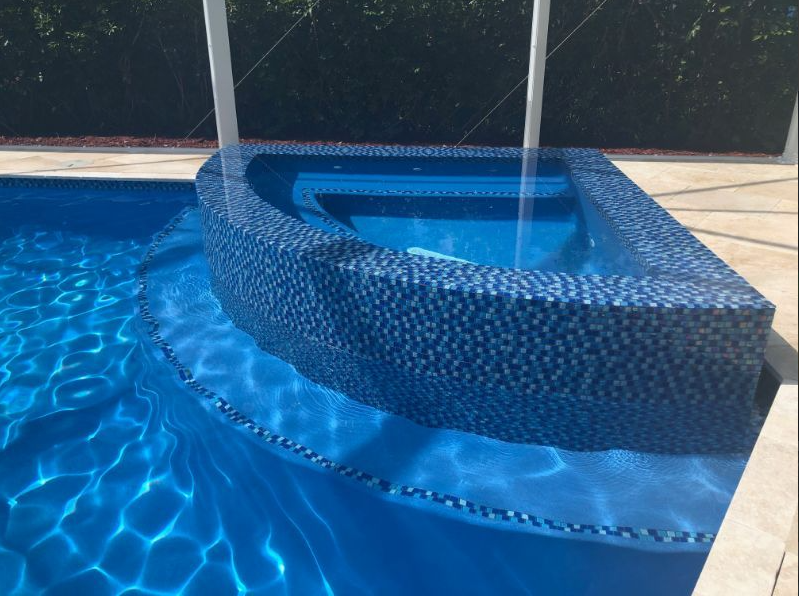 A blue swimming pool with a waterfall in the middle
