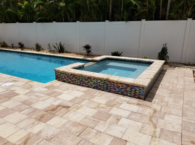 A large swimming pool with a hot tub next to it.