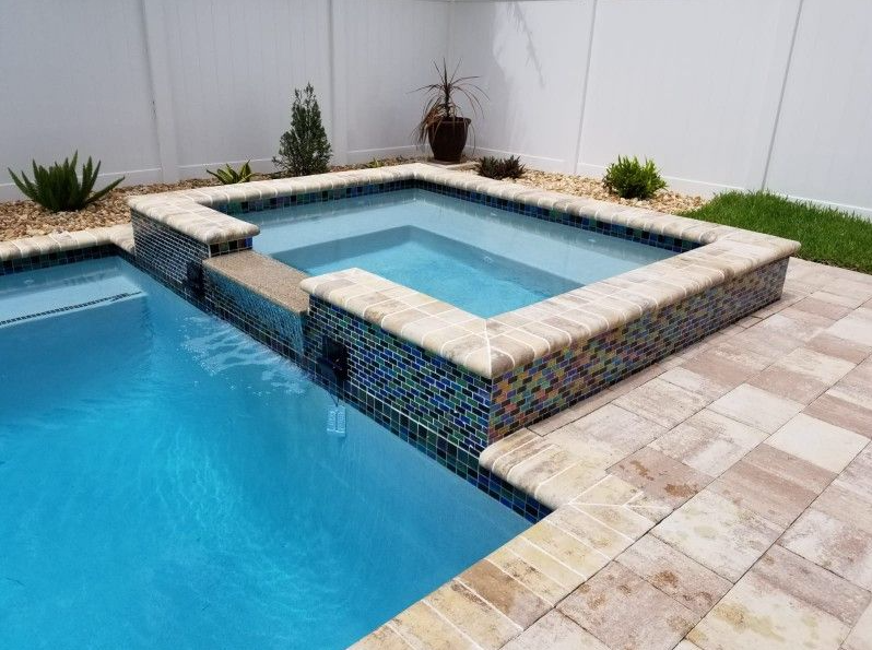A large swimming pool with a hot tub in the middle of it.