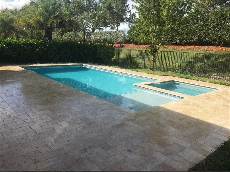 A large swimming pool with a hot tub in the backyard
