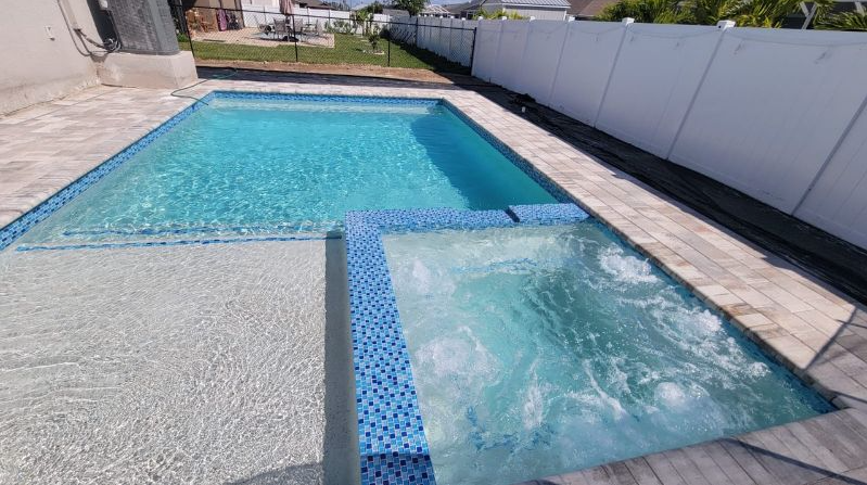 A large swimming pool with a hot tub in the middle of it.
