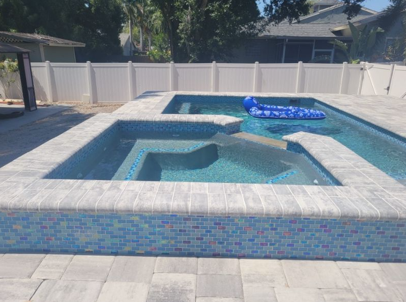 A large swimming pool with a white fence and a blue raft in it.