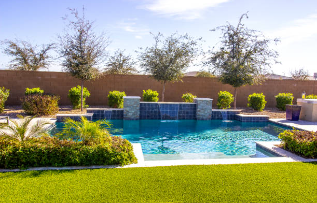 There is a large swimming pool in the backyard of a house.