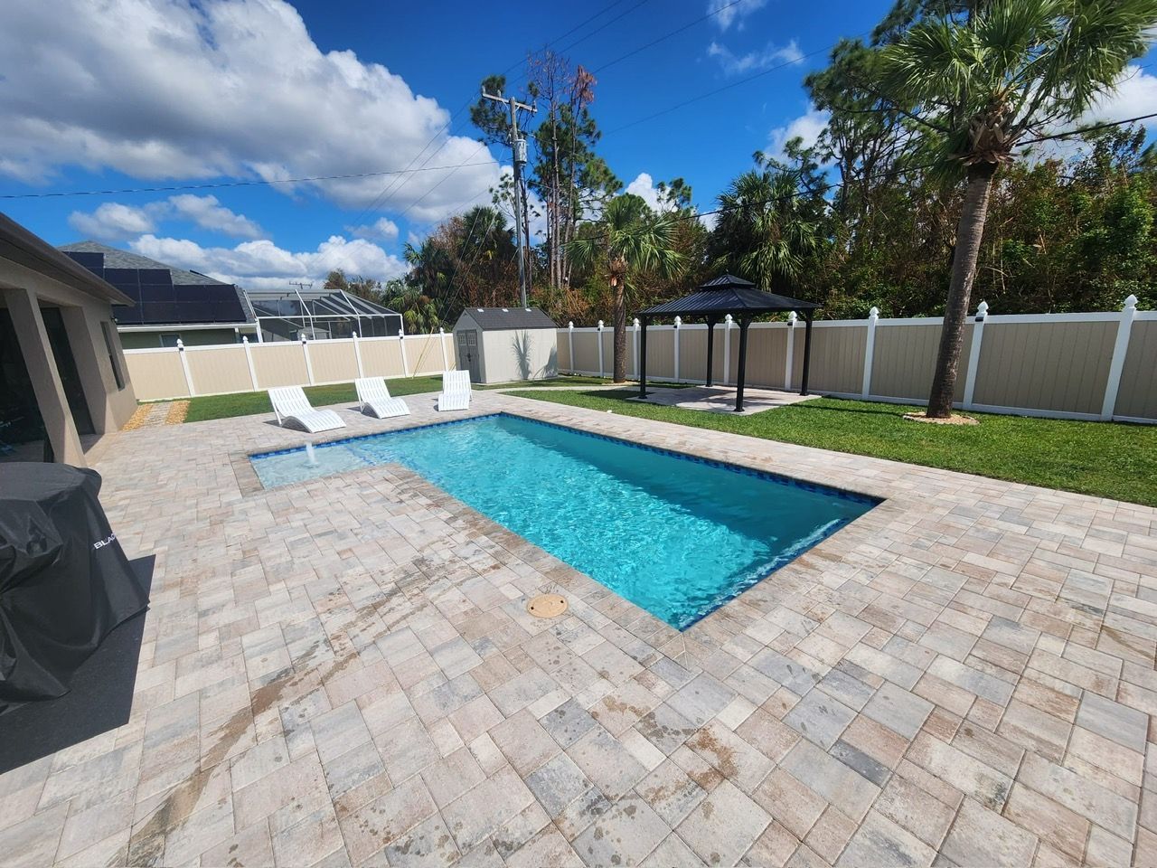 There is a large swimming pool in the backyard of a house.