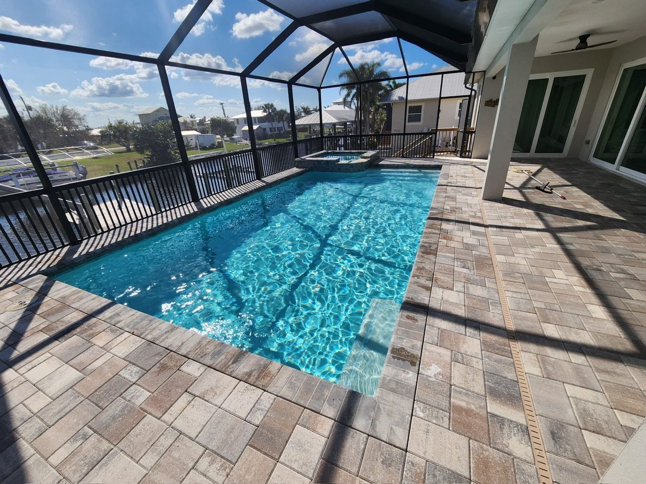 A large swimming pool is surrounded by a screened in area.