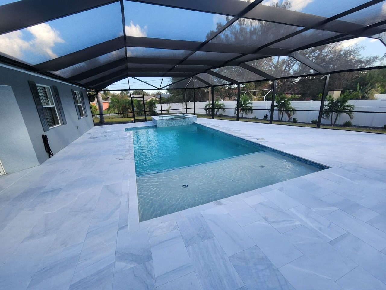 A large swimming pool is covered by a screened in area.