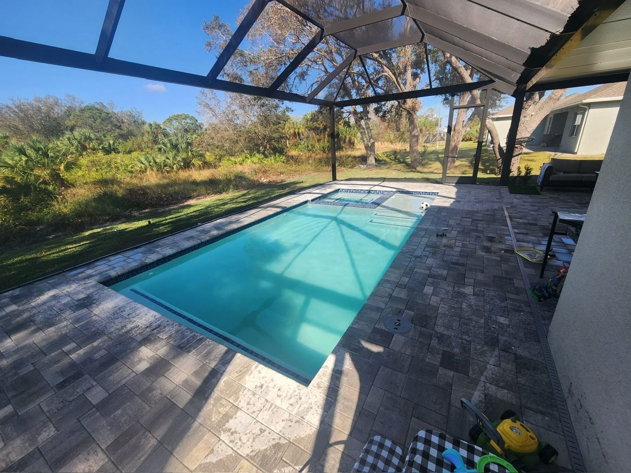 A large swimming pool is surrounded by a screened in area.