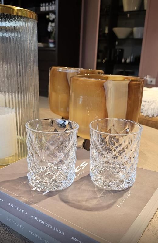 Due bicchieri di cristallo e tre bevande color ambra su un libro al tavolo di un bar o di una sala da pranzo.