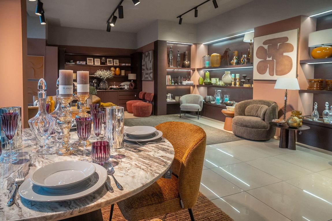 Sala da pranzo moderna con tavolo apparecchiato, pavimento in marmo e sedie e decorazioni contemporanee.