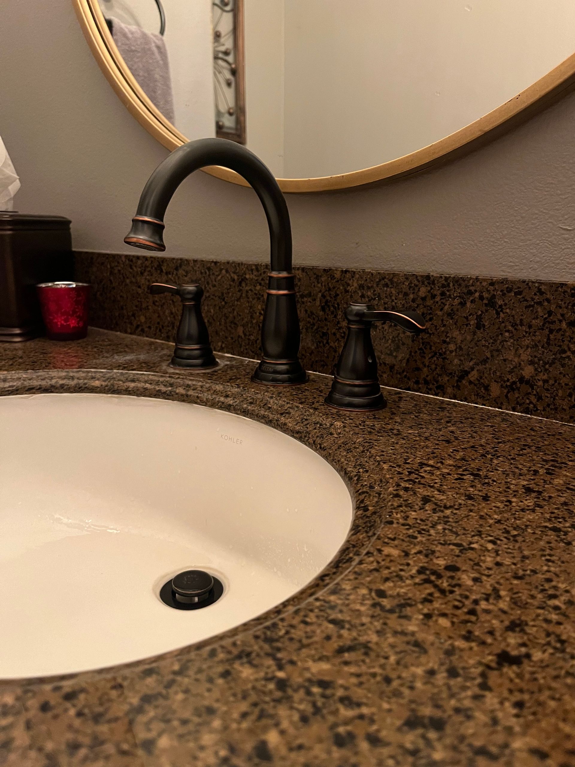 A bathroom sink with a black faucet and a mirror.