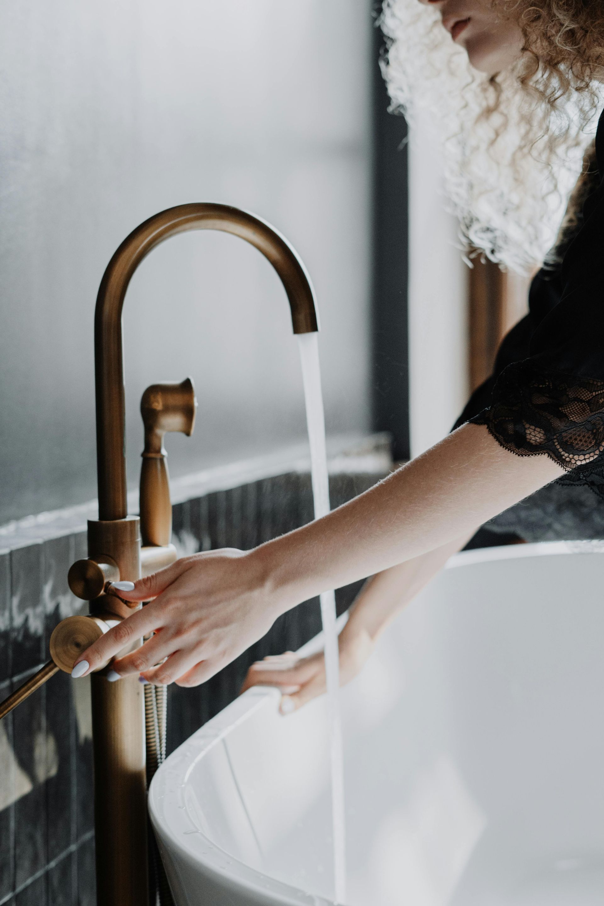 A woman is washing her hands in a bathroom sink.