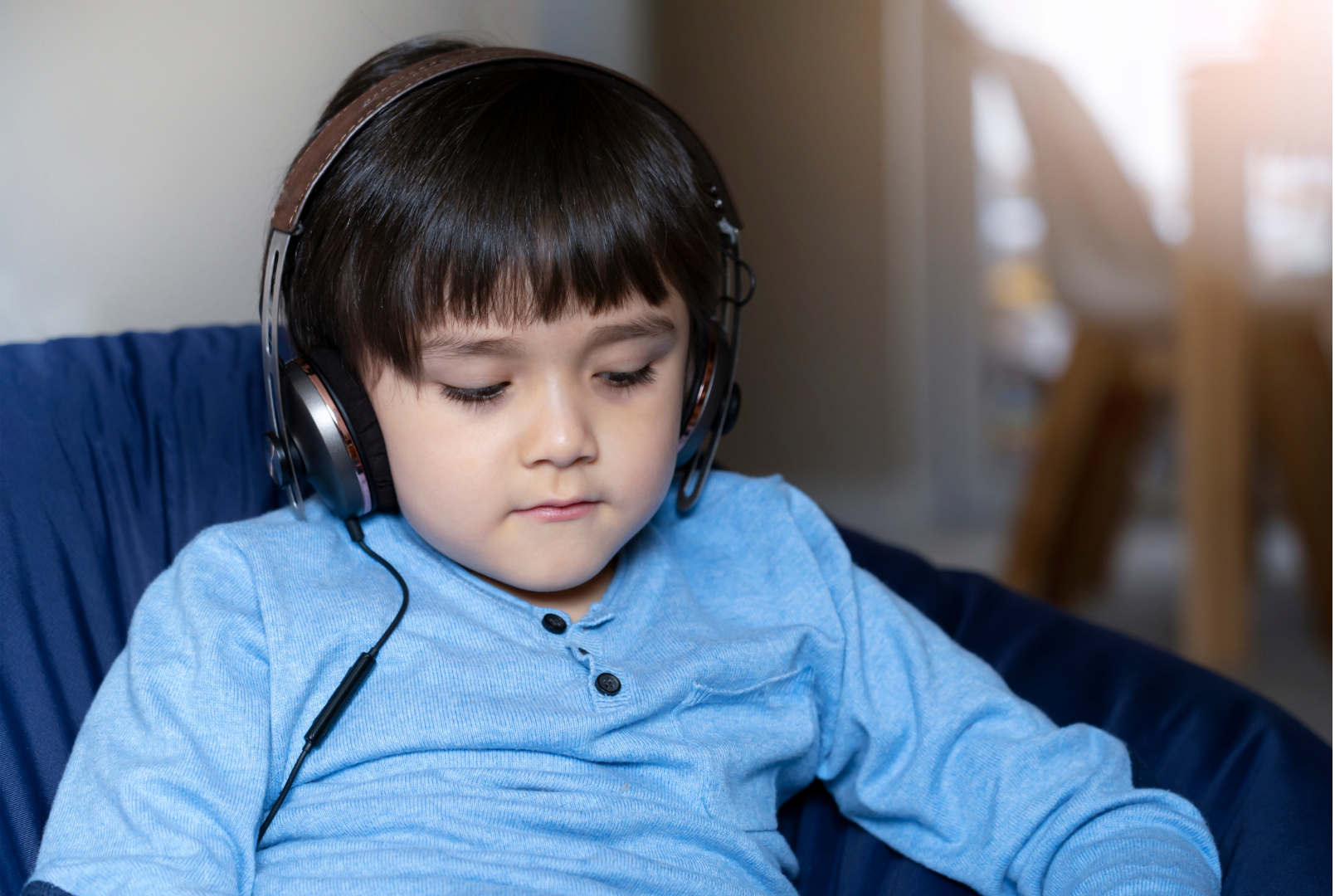a young boy wearing headphones is sitting on a bean bag chair .