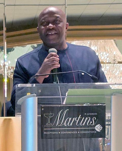 Finance Minister Ngafuan speaking at a podium. He wears a navy blue shirt and holds a microphone. 