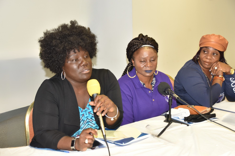 Three women are sitting at a table talking into microphones. Association of Liberian Journalists female members speaking