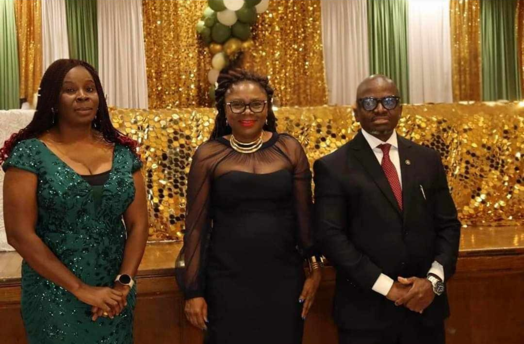 A man and two women are standing next to each other in a room.