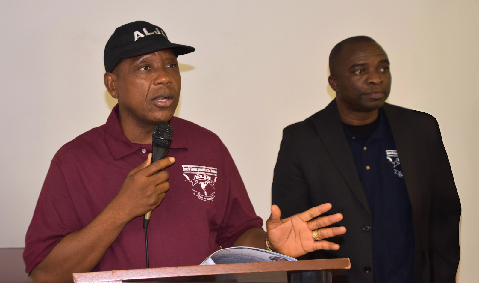 Two men are standing next to each other and one of them is holding a microphone.