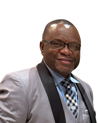 Man wearing glasses, a gray suit with black trim, and a patterned tie, smiling.