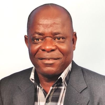 Stanley Seakor in a suit and plaid shirt is smiling for the camera.