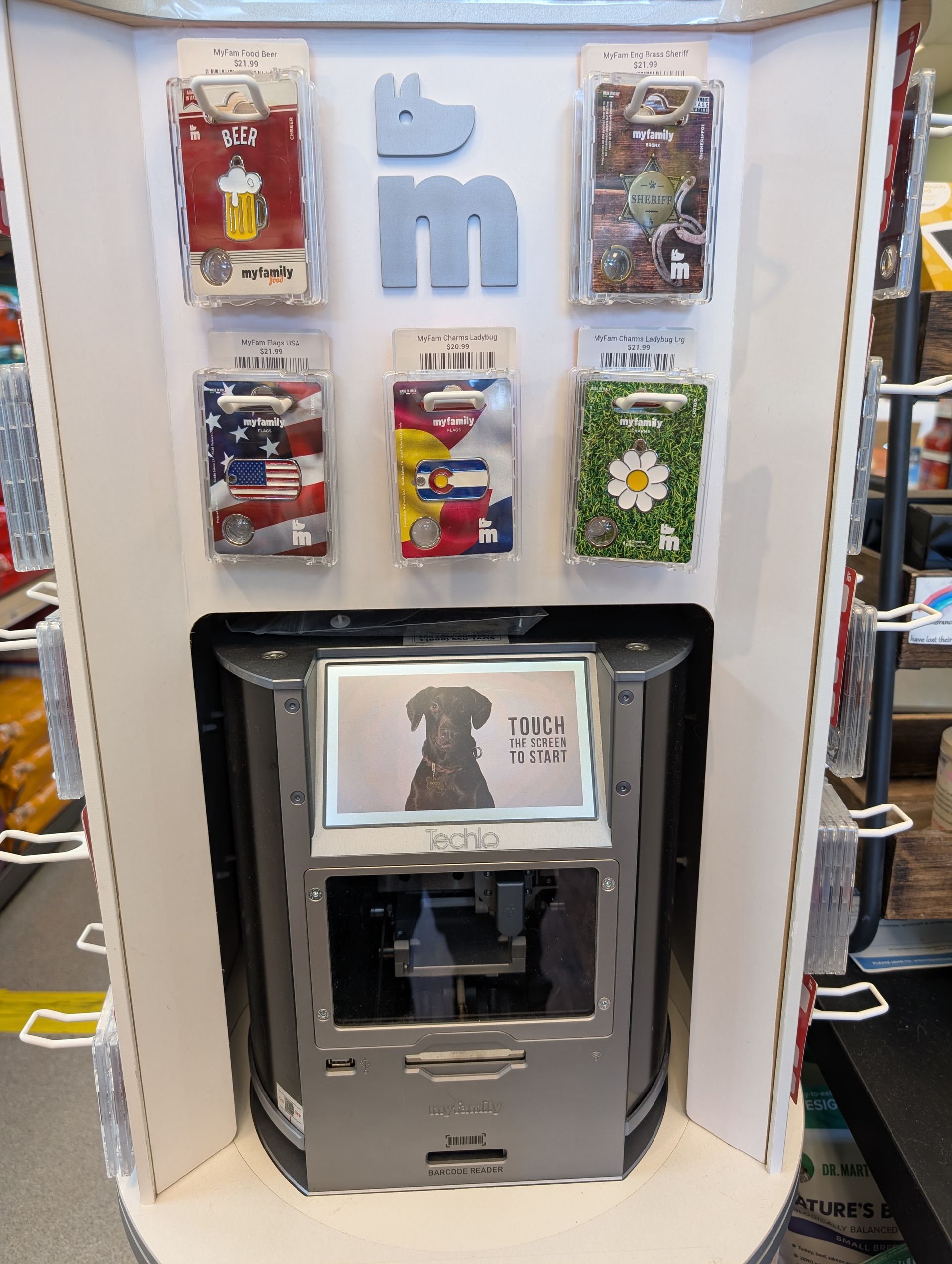 Display case with phone cases, dog logo, and payment kiosk.