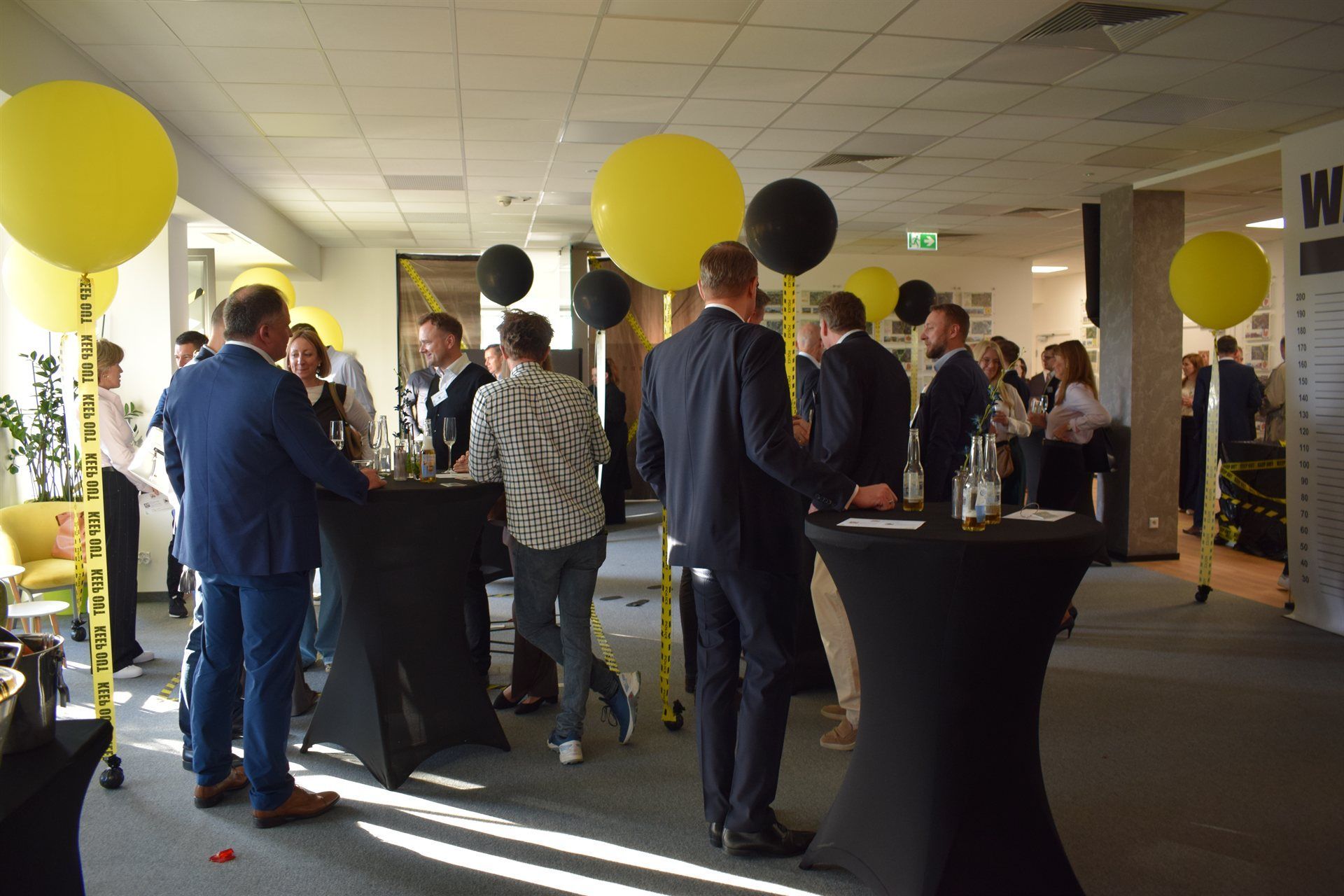 Networking event mit Geschäftspartnern in einem Raum der mit gelben und schwarzen Ballons dekoriert ist.