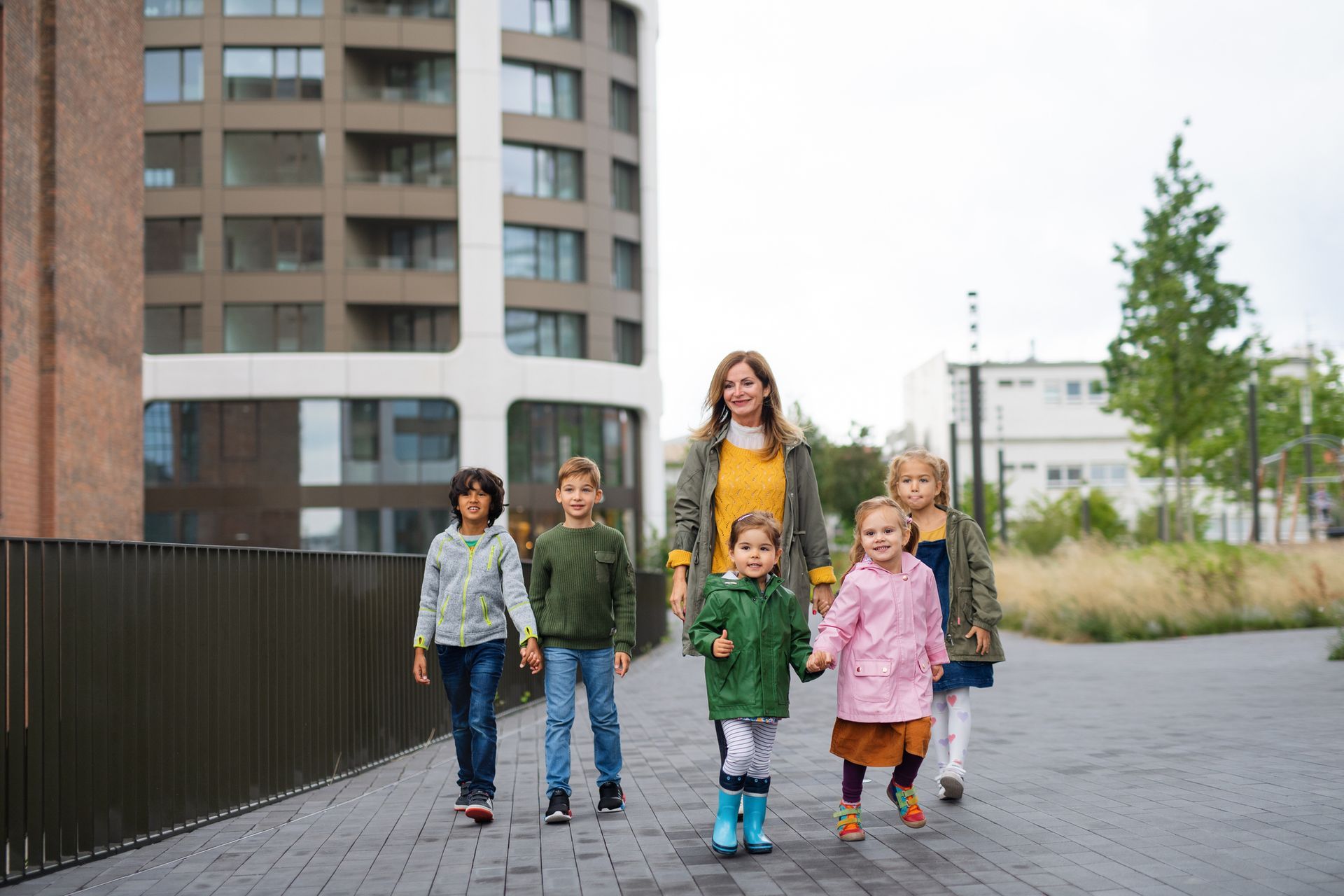 Small group of children on a walk with their teacher outside.