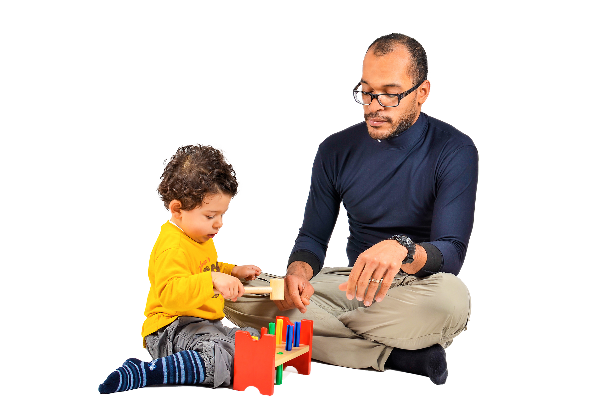 Man and young child playing with wooden toy. Man watches child hammering pegs.