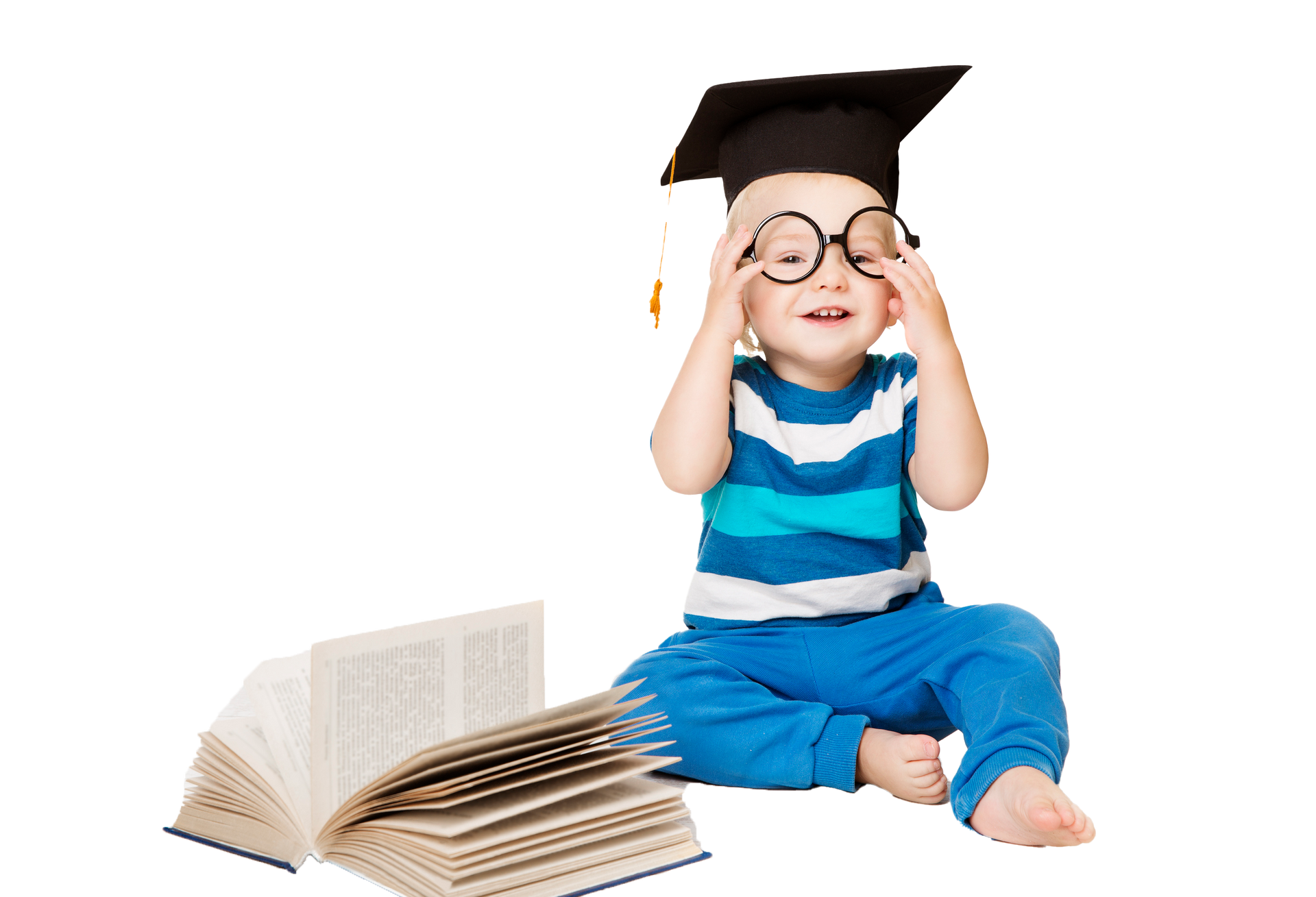 A toddler in graduation cap and glasses, laughing, sitting near an open book.