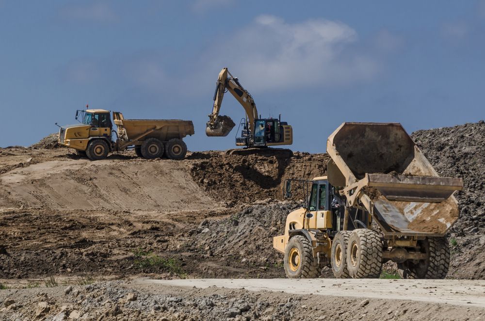A Dump Truck Is Being Loaded With Dirt By An Excavator — Territory Industries Pty Ltd In Uralla, NT