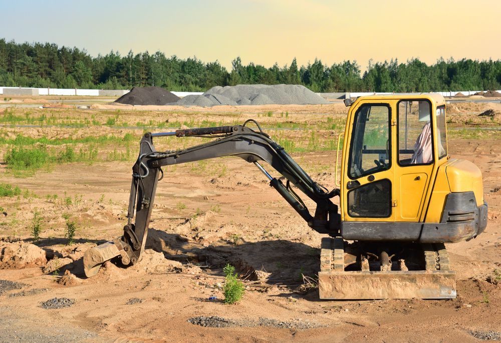 A Yellow Excavator Is Sitting In The Middle Of A Dirt Field — Territory Industries Pty Ltd In Uralla, NT