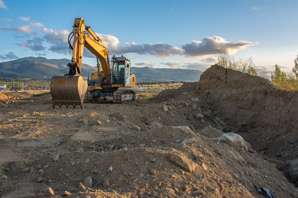 A Yellow Excavator Is Digging A Hole In The Dirt On A Construction Site — Territory Industries Pty Ltd In Uralla, NT